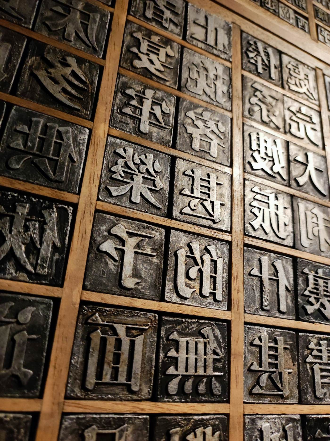 Rows of worn metal movable-type blocks seen close, their faces catching low light.
